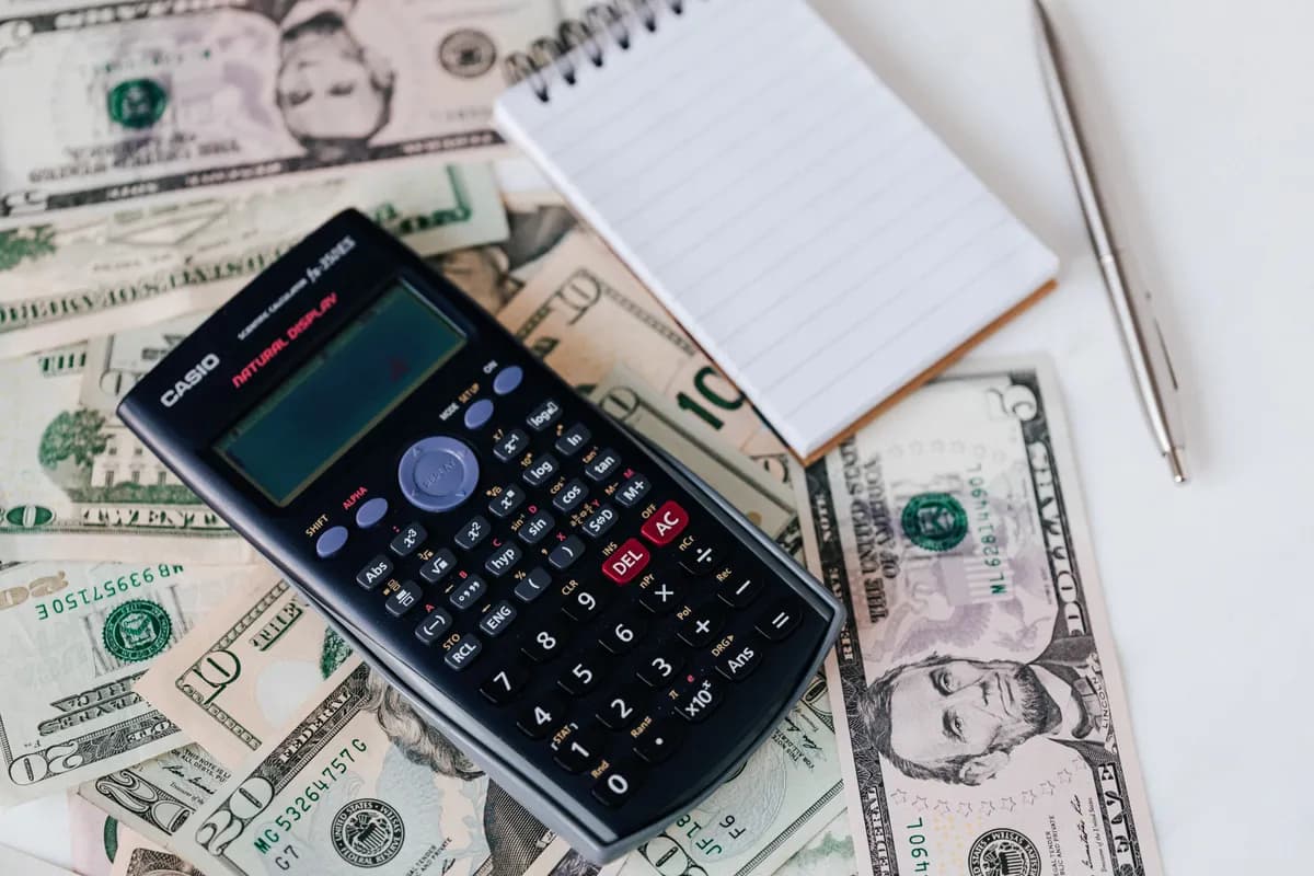 Calculatrice posée sur des billets de banque, illustrant le coût caché du trading