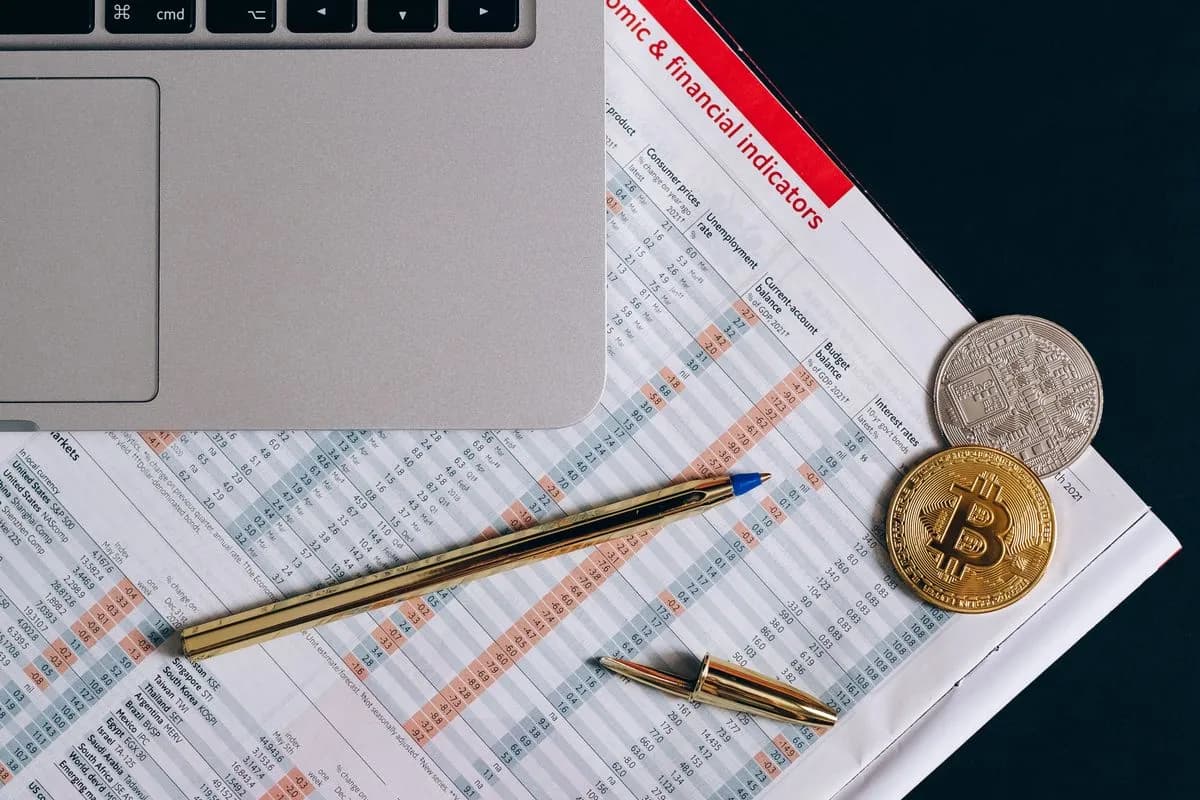 Vue de dessus de documents financiers, d'un ordinateur portable et de pièces de crypto-monnaie
