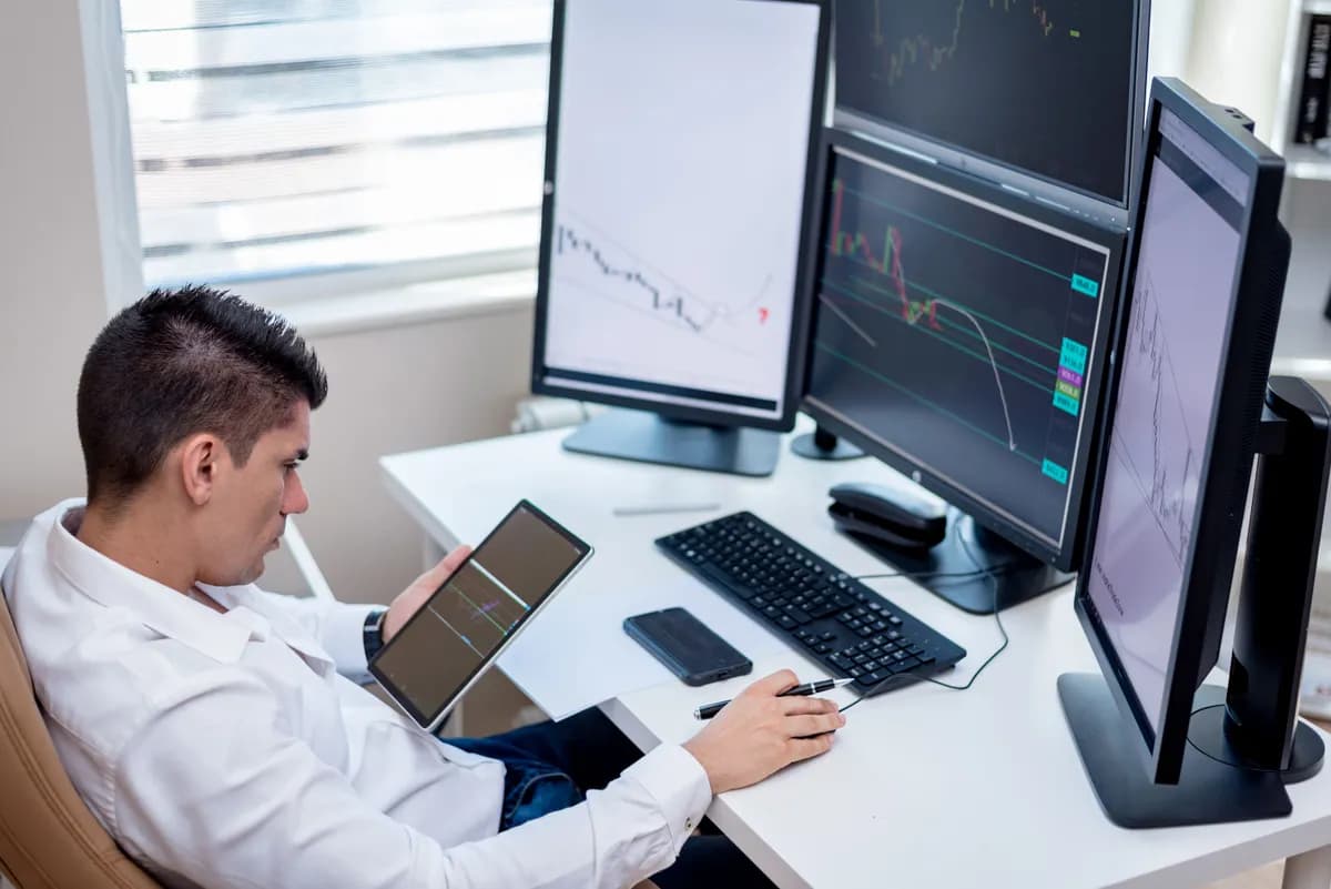 Trader pratiquant le scalping trading devant plusieurs écrans avec graphiques en temps réel
