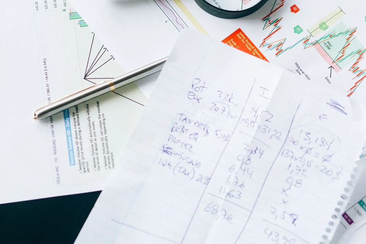 Notes manuscrites de calculs posées sur des graphiques de marché imprimés